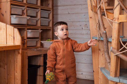 Boy toddler in kids room for decoration design. Modern wood Interior design. Light background. Montessori toys