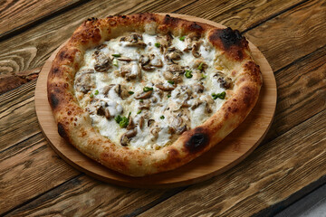 Mushroom pizza, pizza with addition of edible forest mushrooms porcini mushrooms, chanterelle and mozzarella cheese and herbs on a wooden rustic table