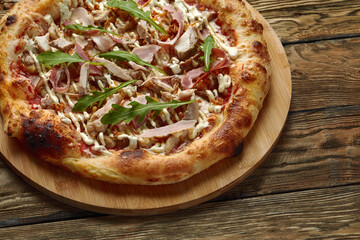 neapolitan Pizza with Mozzarella cheese, bacon, ham, tomato sauce, chicken, Spices and Fresh arugula. Italian pizza on wooden table background