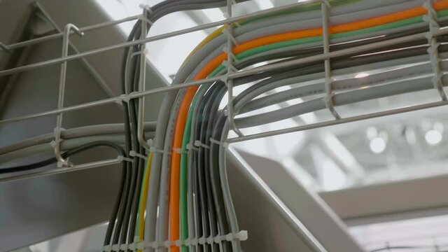 In industrial production many wires of different colors are laid in a metal tray and diverge to their equipment. Shot in motion. Closeup