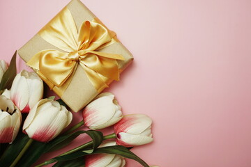 Gift boxes with gold ribbon and tulip flower bouquet on pink background