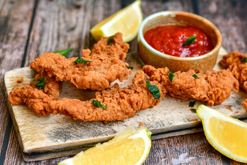 
 Crispy  deep fried   chicken strips and wedges potato. Breaded  with cornflakes chicken  breast fillets  with chilly peppers and fresh   basil on wooden rustic background