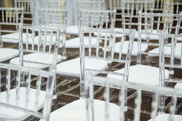 Glass chairs stand in a row in a beautiful wedding outing ceremony
