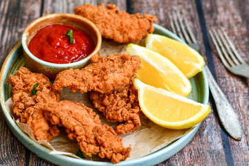
 Crispy  deep fried   chicken strips and wedges potato. Breaded  with cornflakes chicken  breast fillets  with chilly peppers and fresh   basil on wooden rustic background