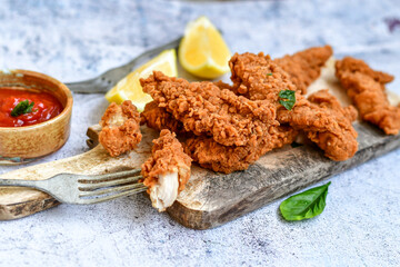 
 Crispy  deep fried   chicken strips and wedges potato. Breaded  with cornflakes chicken  breast fillets  with chilly peppers and fresh   basil on wooden rustic background