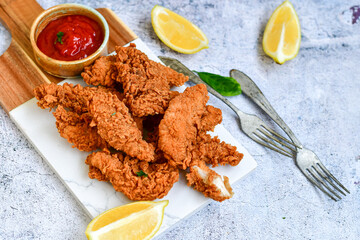 
 Crispy  deep fried   chicken strips and wedges potato. Breaded  with cornflakes chicken  breast fillets  with chilly peppers and fresh   basil on wooden rustic background