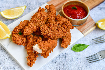 
 Crispy  deep fried   chicken strips and wedges potato. Breaded  with cornflakes chicken  breast fillets  with chilly peppers and fresh   basil on wooden rustic background