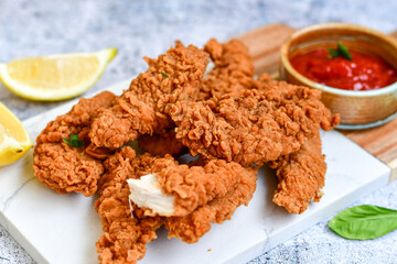 
 Crispy  deep fried   chicken strips and wedges potato. Breaded  with cornflakes chicken  breast fillets  with chilly peppers and fresh   basil on wooden rustic background
