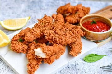 
 Crispy  deep fried   chicken strips and wedges potato. Breaded  with cornflakes chicken  breast fillets  with chilly peppers and fresh   basil on wooden rustic background