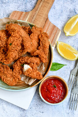
 Crispy  deep fried   chicken strips and wedges potato. Breaded  with cornflakes chicken  breast fillets  with chilly peppers and fresh   basil on wooden rustic background