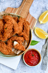 
 Crispy  deep fried   chicken strips and wedges potato. Breaded  with cornflakes chicken  breast fillets  with chilly peppers and fresh   basil on wooden rustic background
