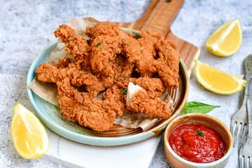 
 Crispy  deep fried   chicken strips and wedges potato. Breaded  with cornflakes chicken  breast fillets  with chilly peppers and fresh   basil on wooden rustic background