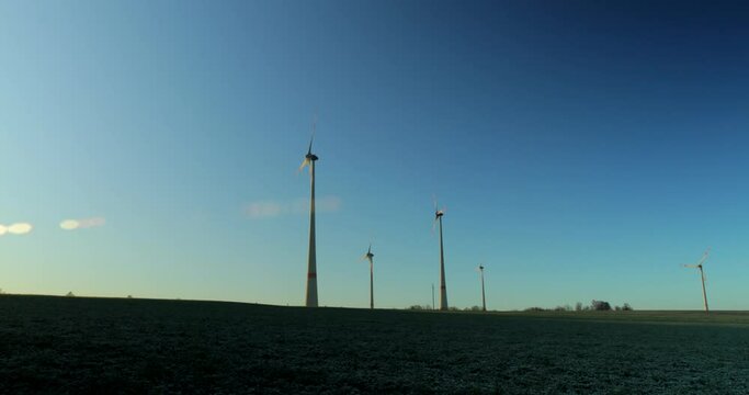 Time-lapse of an cold morning as the sun rises on a small wind farm with a small agricultural farm in the foreground with planes going by.