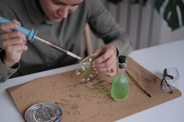 Stained glass maker works with colorful souvenirs. Female hands soldering the stained glass, learning how to make stained glass, finishing handicrafts, soldering gun
