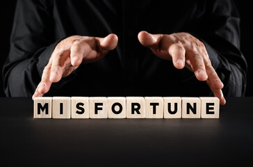 Male hands over the wooden blocks with the word misfortune.