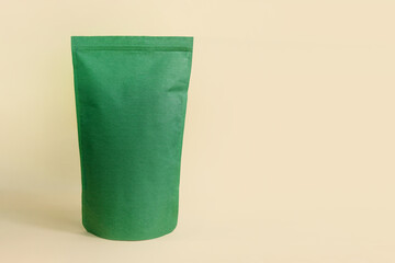 Green pouch bag mockup neutral beige background monochrome. Blank emerald recycled paper pack...
