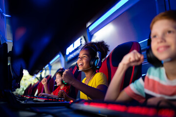 Group of cheerful excited children or professional gamers playing video games on computer in game...
