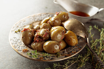 Bowl with olives and thyme twigs on a stone table.