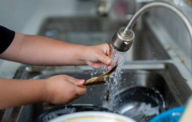 Close up hands washing spoon and fork