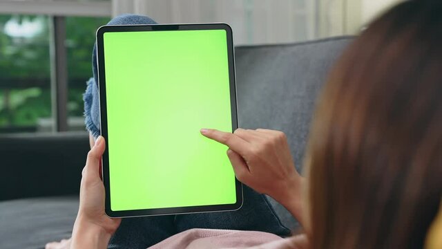 Woman holding in hands a digital tablet with green screen for internet online, chroma key screen for advertising.