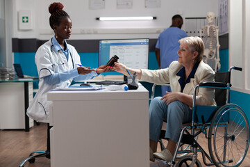 Physician doctor holding pills bottle explaining sickness diagnosis to senior invalid woman...