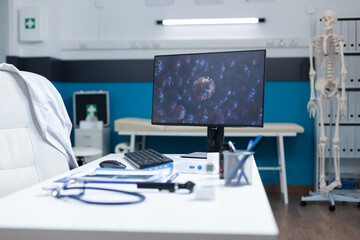 Empty modern office with computer standing on desk table having virus cell on screen during coronavirus global pandemic. Examination room equipped with professional tools. Medicine concept