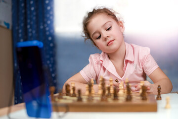 girl plays chess with an opponent on the phone. home mode