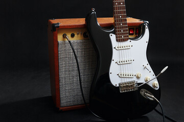 Naklejka premium Combo for guitar with black guitar on black background.