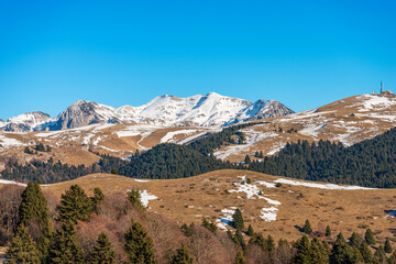Fototapeta premium Winter landscape of Lessinia plateau (Altopiano della Lessinia) and mountain range of the Monte Carega (small Dolomites) and Monte Tomba, Velo Veronese, Verona province, Veneto, Italy, Europe.