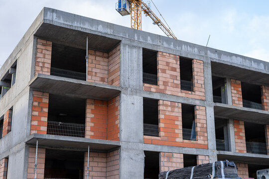Fototapeta budowa bloków z czerwonej cegły i szarego betonu i żółtym dźwigiem 