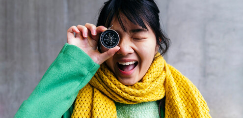 Cheerful woman covering eye with compass