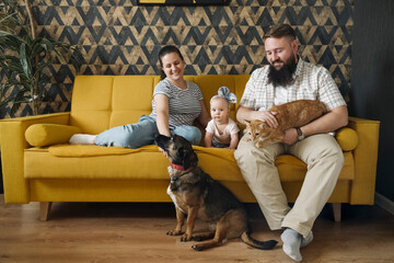 Smiling family with baby girl and pets in living room