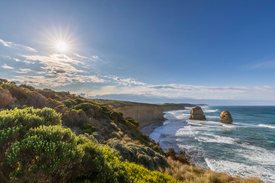 Australia, Victoria, Sun shining over Twelve Apostles and Gibson Steps in Port Campbell National Park at sunrise