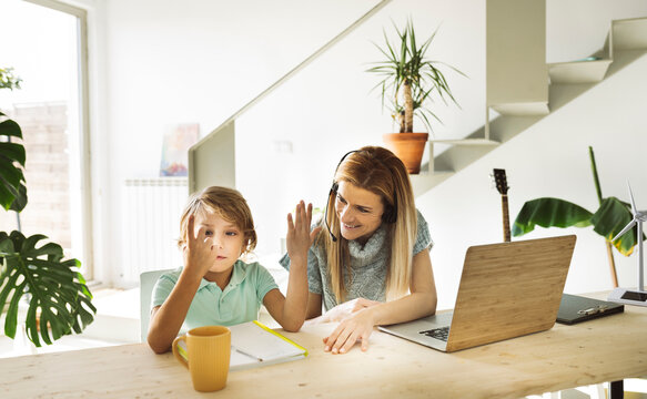 Smiling woman looking at son counting fingers at home