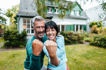 Cheerful mature couple showing fists in backyard