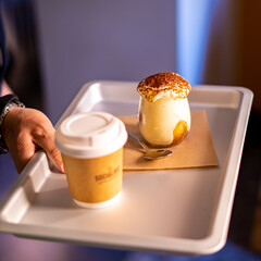 Man holding tray with take away coffee and Tiramisu in glass. coffee flavored Italian dessert made of ladyfingers and mascarpone
