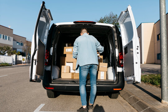Man standing near packages in delivery van