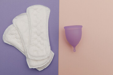 Menstrual cup and sanitary pads on a colorful background. Top view. Concept of women's hygiene and health care