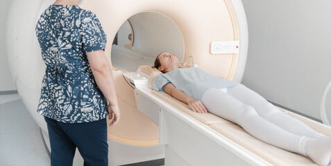 Doctor or nurse and patient with tomography CT or MRI Scan in hospital. Interior of radiography...