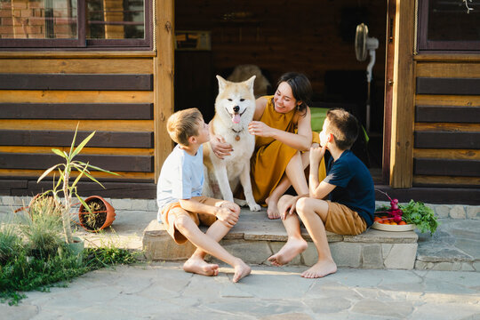 Happy family sitting outside house with Akita dog