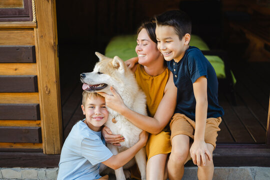 Happy family embracing their Akita dog sitting outside house