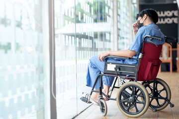 Fototapeta na wymiar Male patient sitting wheelchair looking through window in hospital.
