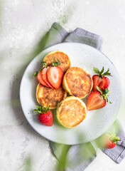 Cottage cheese pancakes or fritters with strawberry and natural yogurt. Healthy breakfast or lunch. Syrniki. Top view.