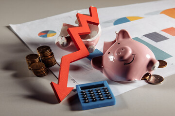 Crisis and bankruptcy concept. A broken piggy with coins and arrow down on business diagram