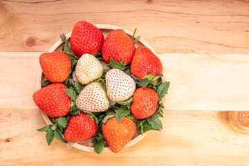 Fresh strawberries in a wooden basket on wooden background, Red Strawberries and white strawberries Pine berry or Hula strawberry in Bamboo basket.