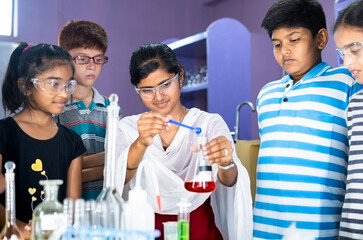 Pan shot of Teacher Explaining about science experiment to students with Eye Protection Glasses at chemistry laboratory - Concept of Education, workshop and Teaching