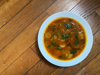 A white bowl of traditional South Indian curry sauce Sambhar gravy on a wooden texture background