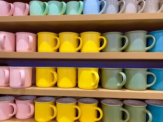 Colourful ceramic mugs displayed for sale in a shop.