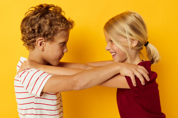 Boy and girl cuddling fashion childhood entertainment yellow background