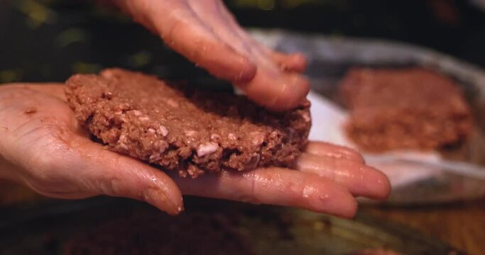 Plant based Impossible Burger meat patties un-cooked being prepared and formed shaped by white caucasian hands to be cooked and grilled - in Cinema 4k (30fps slow from 60fps).